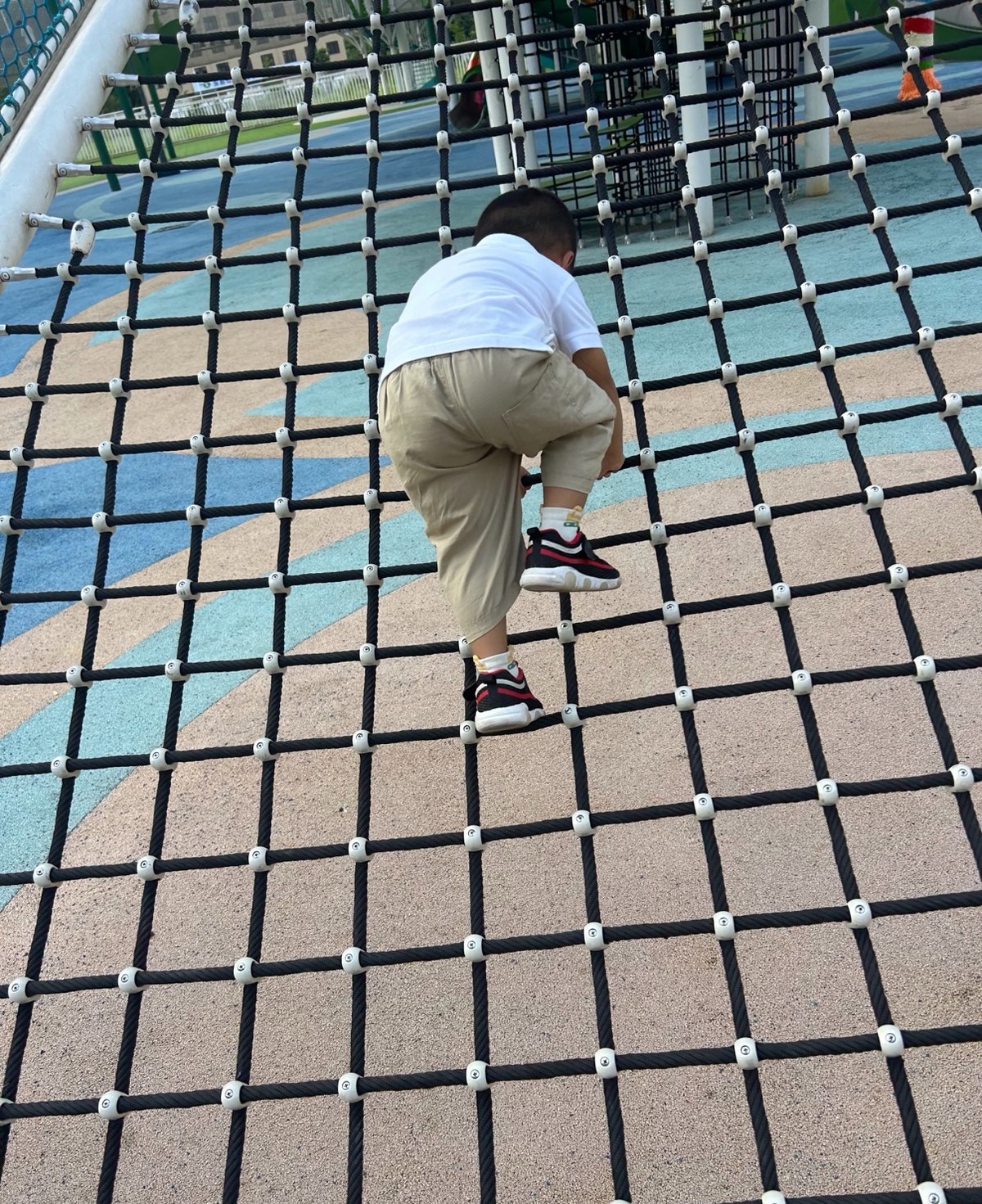 Child climbing a steep black cargo net