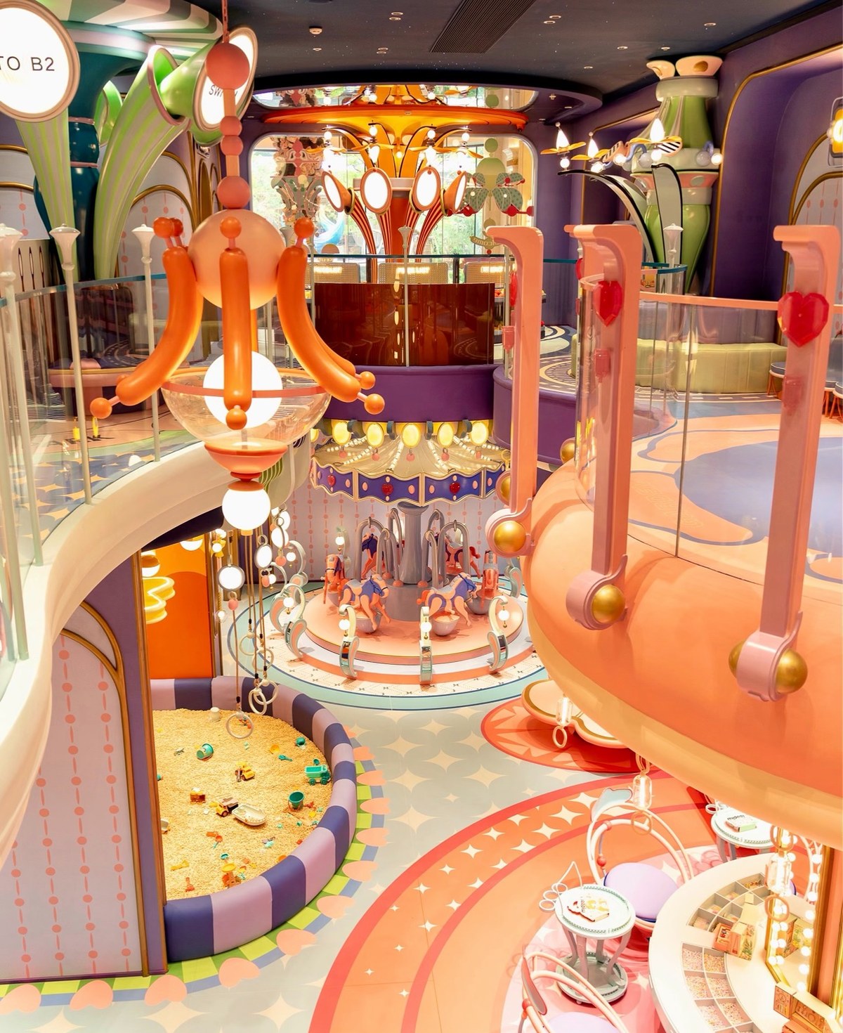 Two-level pastel indoor playground built around a carousel