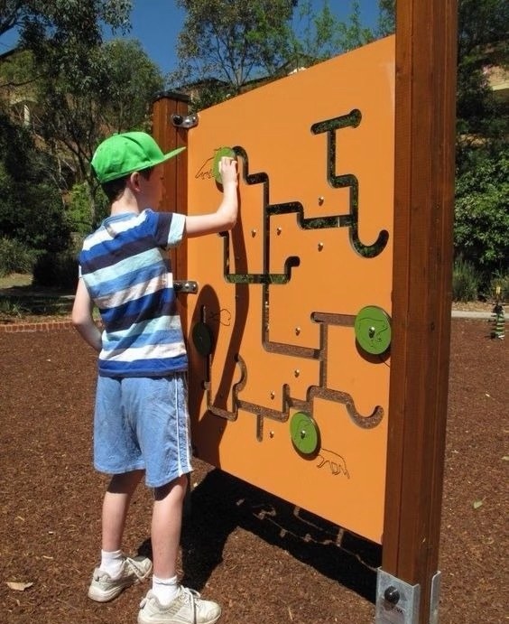 Boy solving a wall maze panel outdoors