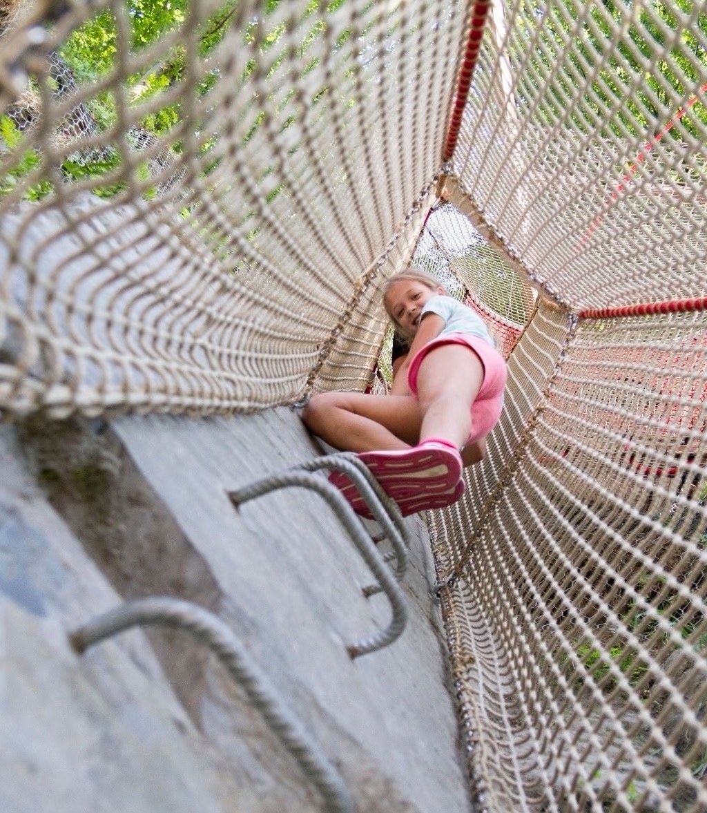 Girl descending a netted chute slide