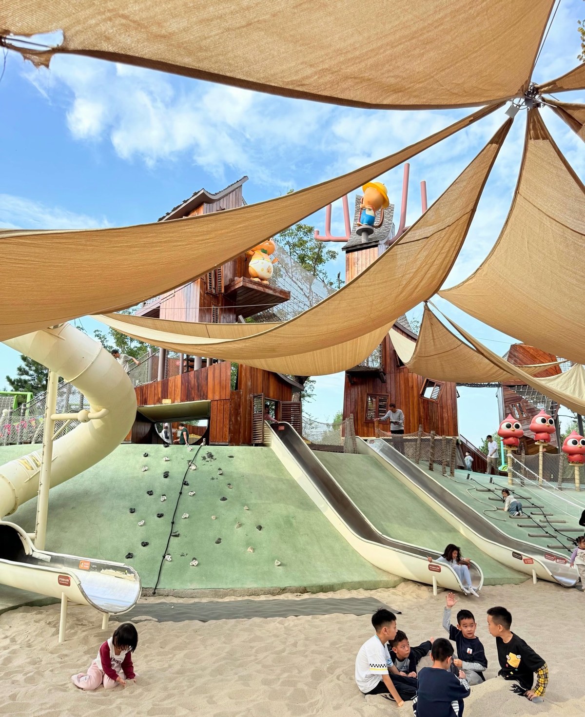 Timber playground with steel slides and sand pit under shade sails