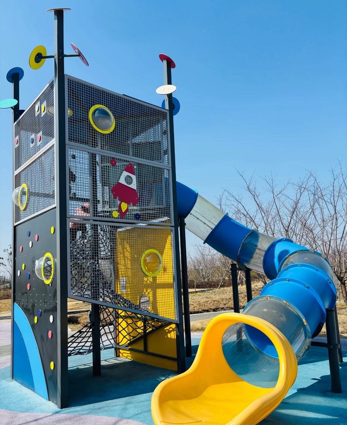 Colourful play tower with a blue tube slide and climbing decks