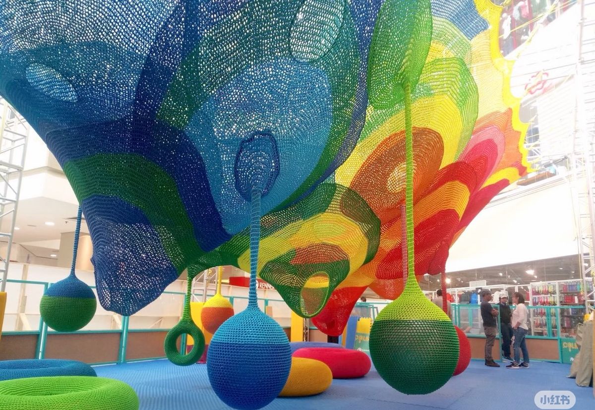 Rainbow crochet net ceiling with hanging play balls in a mall atrium