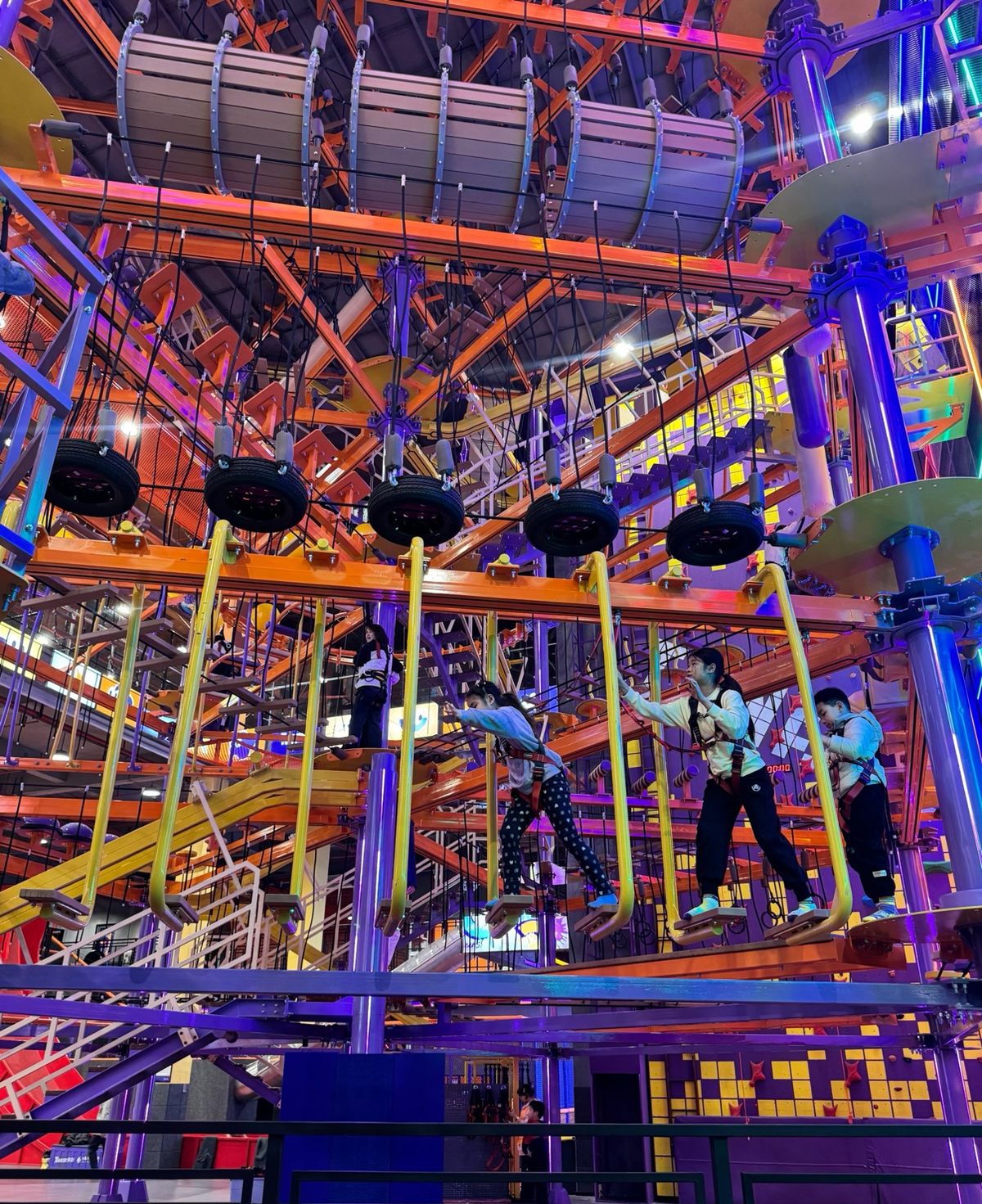 Children on an indoor high-rope course with tyres and balance beams