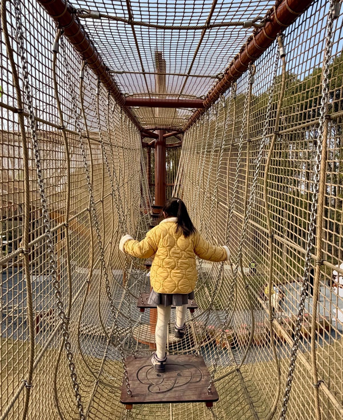 Girl crossing a low net bridge between timber posts