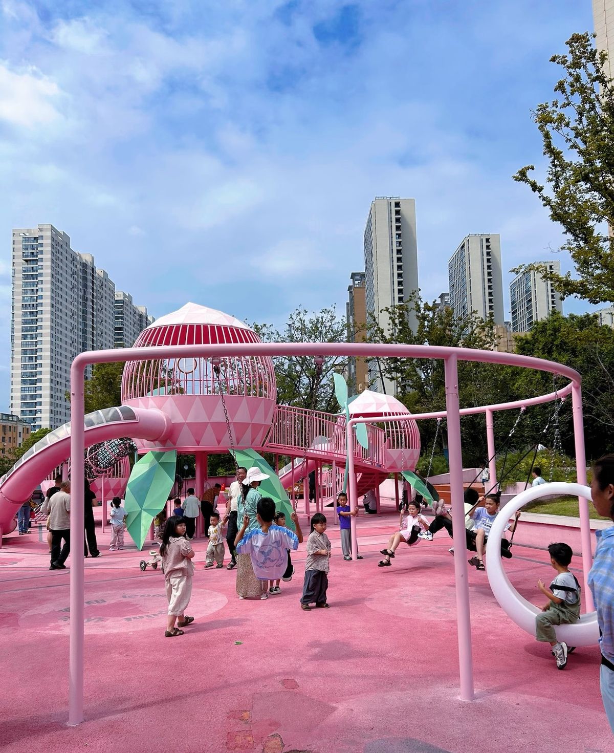 All-pink playground with swings and climbing domes in a city park