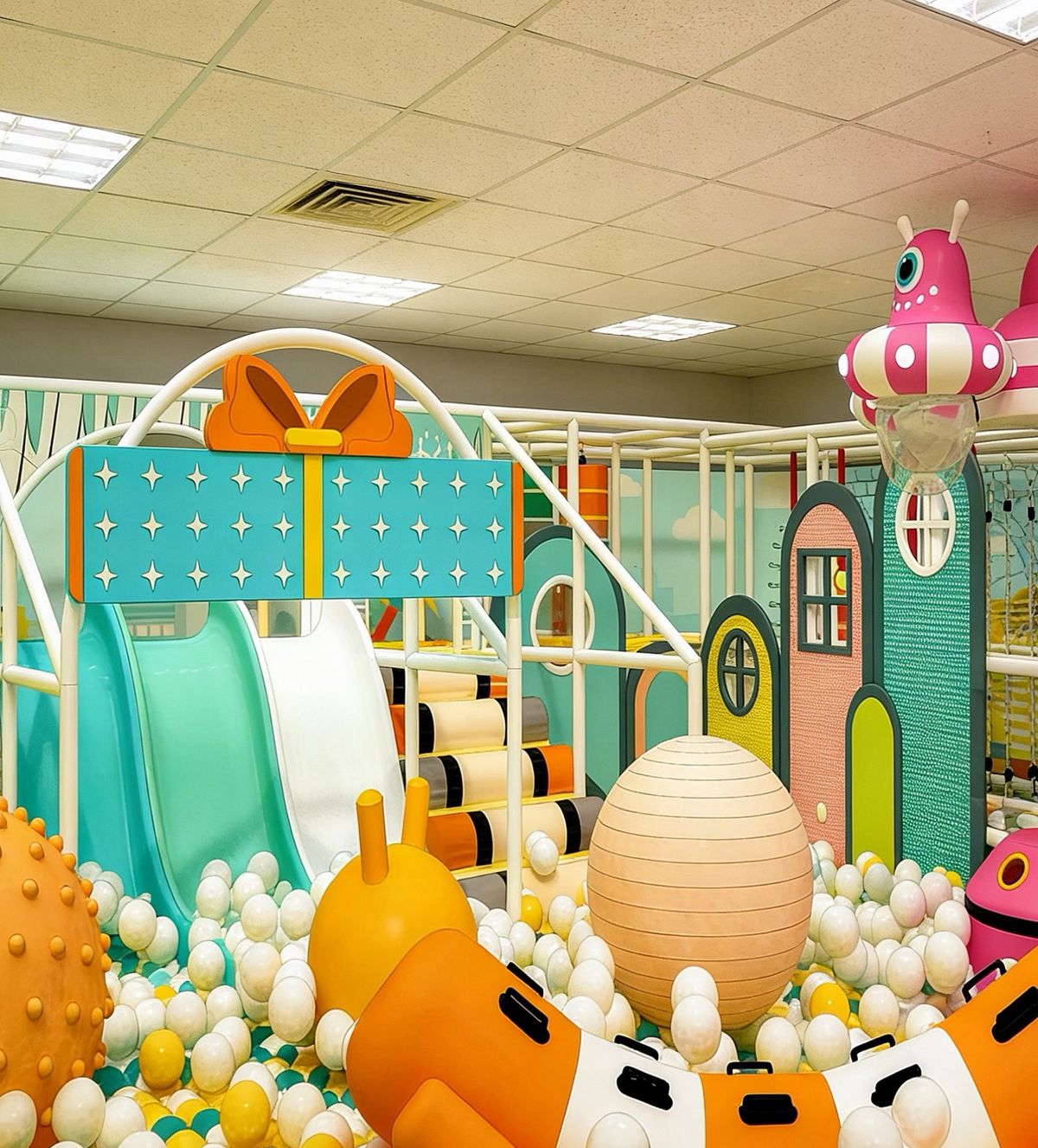 Gift-box themed soft play unit with twin slides and a ball pit