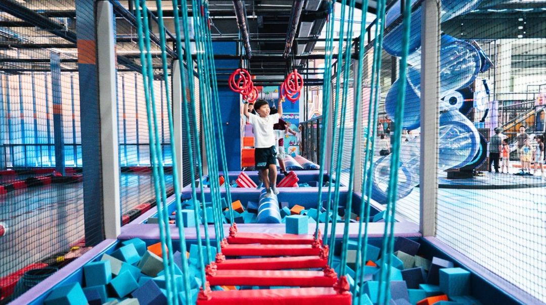 Ninja obstacle course with rings and rope ladder over a foam pit