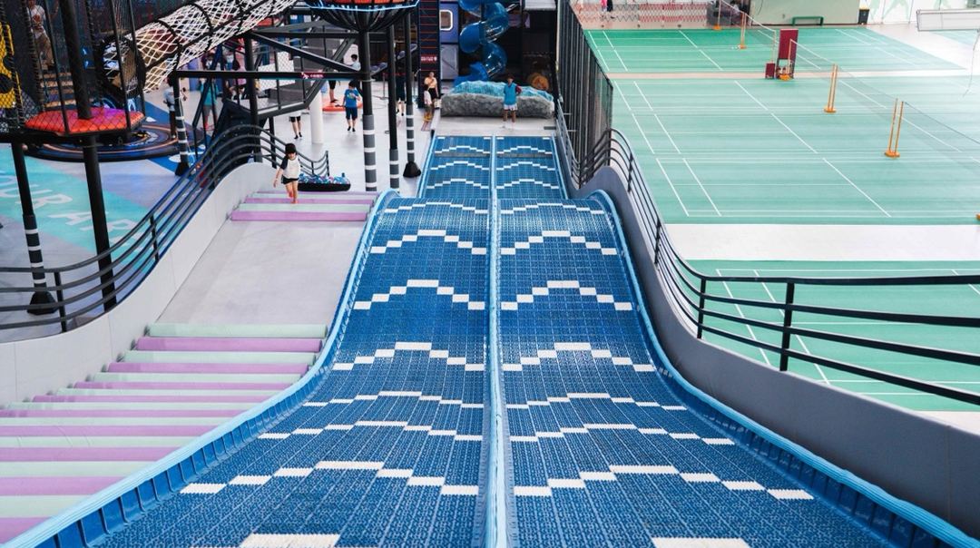 Twin blue wave racing slides inside a sports play hall