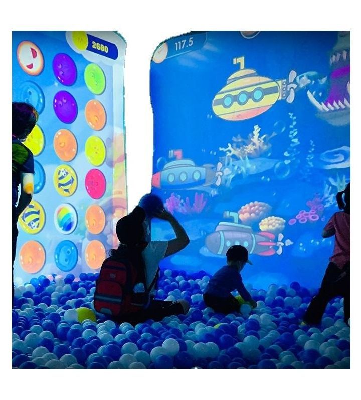 Children playing in a ball pit in front of an interactive projection wall