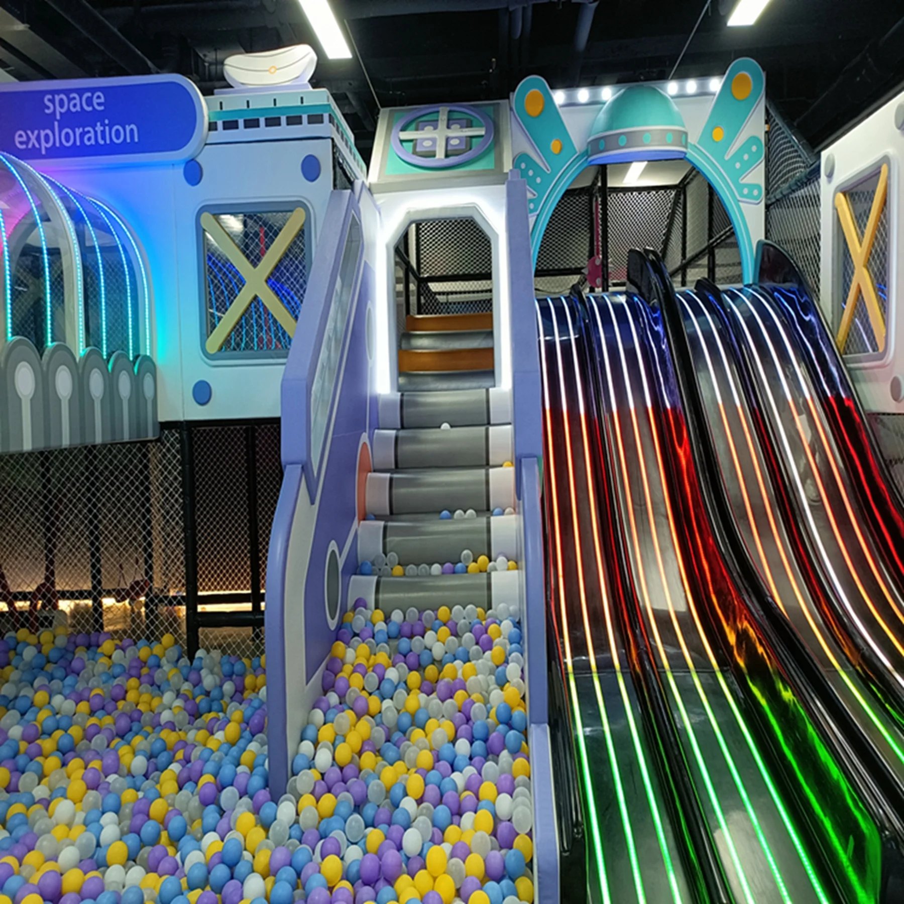 LED rainbow slide and space-themed play capsule in a themed indoor playground