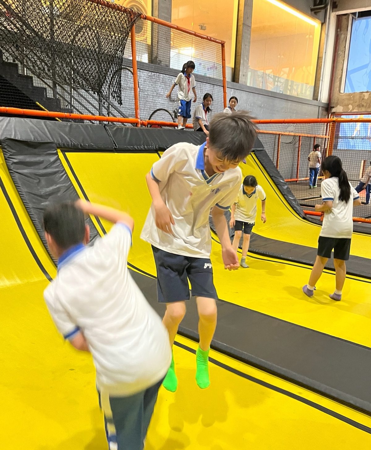 Children bouncing on bright yellow angled wall trampolines