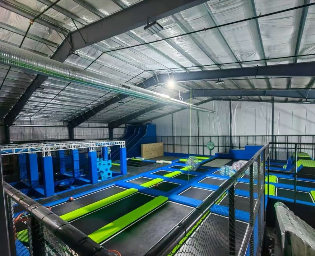 Blue and green trampoline courts with angled walls inside a warehouse hall