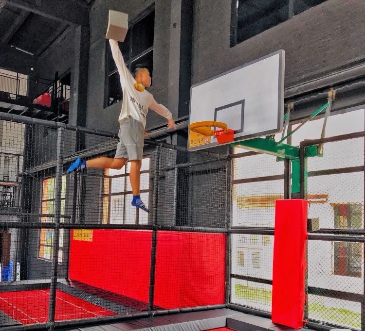 Jumping player dunking a foam block at a padded basketball hoop