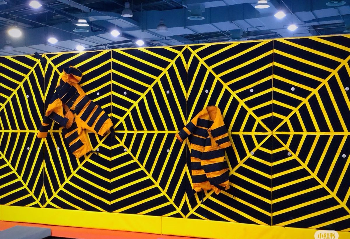 Yellow and black spider web velcro wall with sticky suits hanging on it