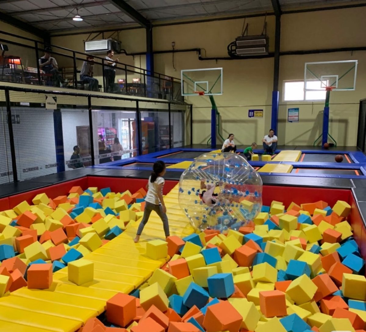 Foam pit with a giant transparent zorb ball and basketball hoops behind